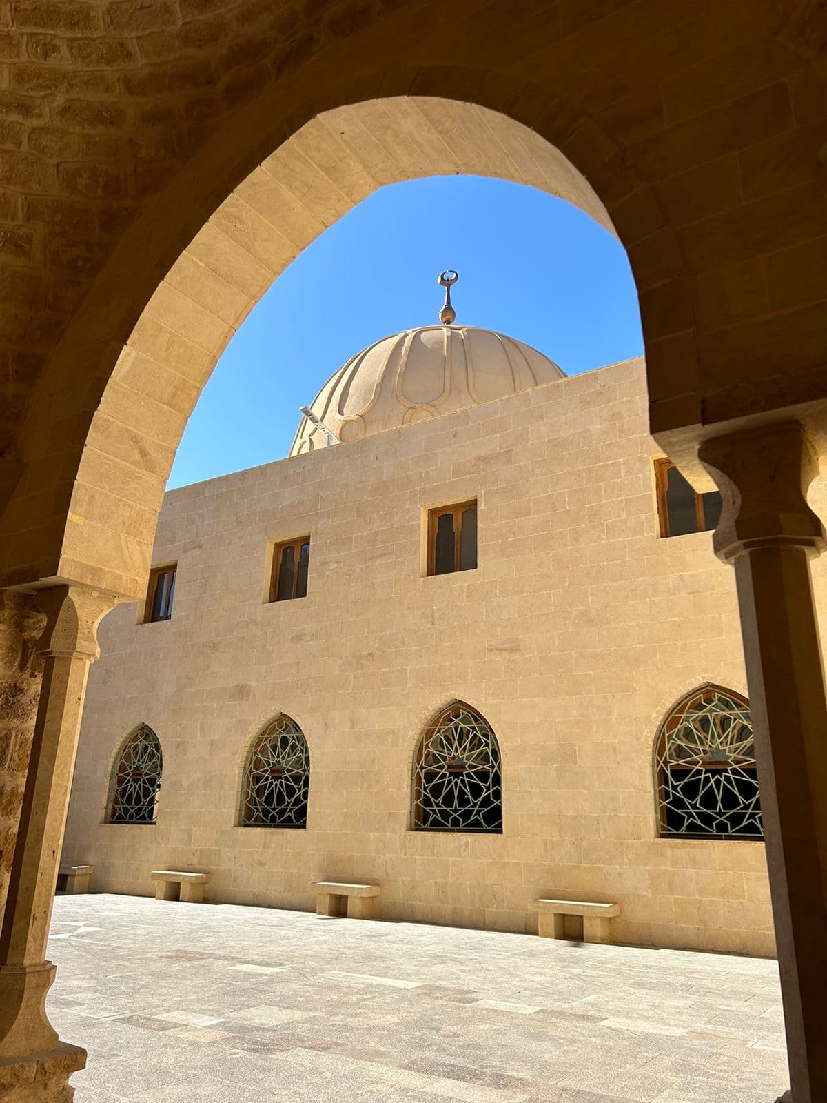 A mosque dome seen through a stone arch